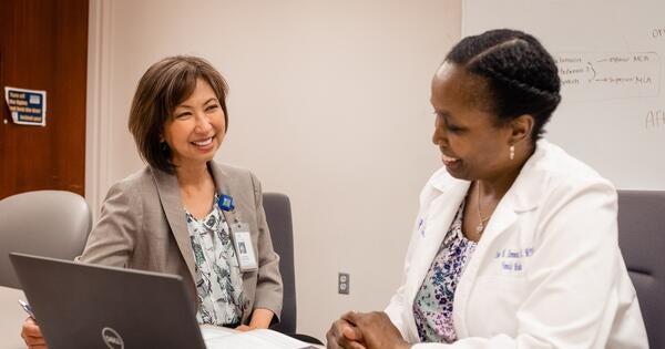 Member of the compliance staff speaking with a faculty member.